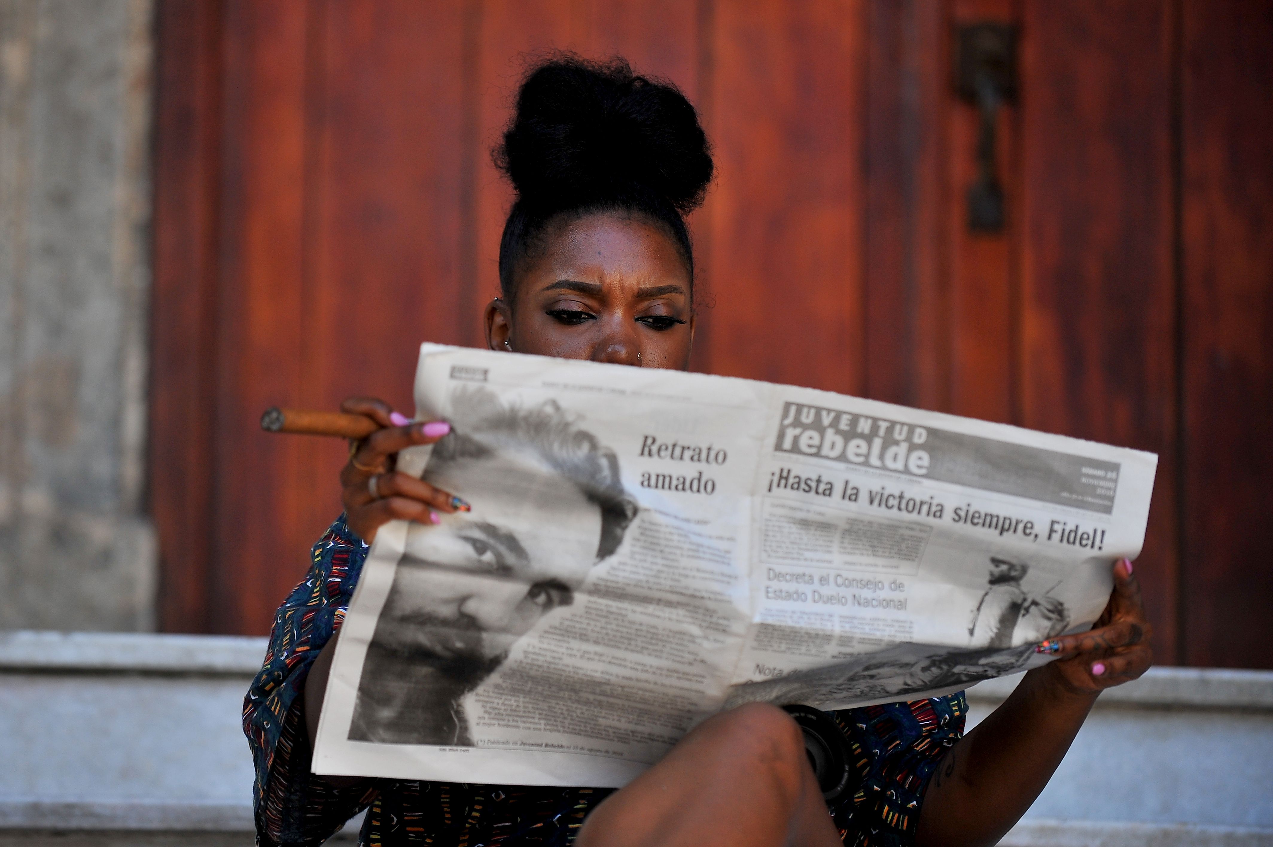 Кубинская женщина читает свежую газету с печальными новостями.