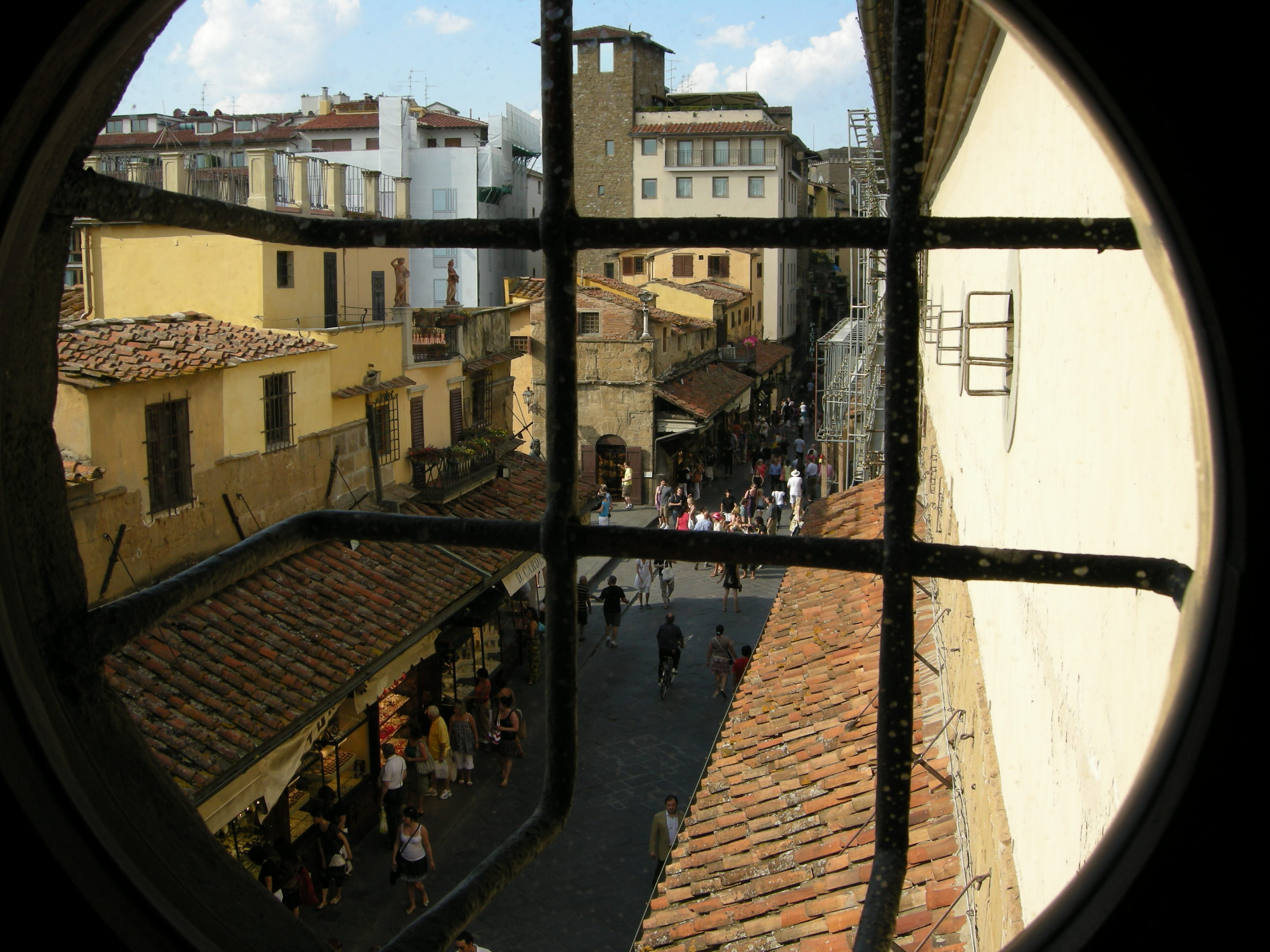 Вид из коридора Вазари на внутреннюю улочку Понте Веккьо. Источник https://upload.wikimedia.org/
